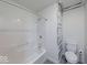 Bathroom with bathtub and shower combo with white tiling and a separated toilet at 32 Downing Dr, Trafalgar, IN 46181