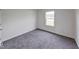 Empty bedroom with neutral walls and grey carpeting with a window at 32 Downing Dr, Trafalgar, IN 46181