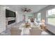 Bright living room with stone fireplace, a ceiling fan, and a large window view at 32 Downing Dr, Trafalgar, IN 46181