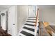 View of the staircase with white risers, a wooden handrail, and a glimpse of the front door at 3701 Sandy Hook Dr, Columbus, IN 47203