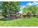 Expansive backyard featuring a brick home with a multi-tiered stone patio and lush green lawn under a blue sky at 5215 Limestone Ct, Indianapolis, IN 46237