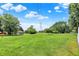 Spacious backyard with lush green lawn, scattered trees, utility tower and small storage sheds under a partly cloudy sky at 5215 Limestone Ct, Indianapolis, IN 46237