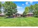 Spacious backyard with a brick home, manicured lawn, shade trees, and a multi-tiered stone patio for outdoor entertaining at 5215 Limestone Ct, Indianapolis, IN 46237