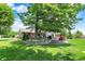 Backyard view showcasing a multi-tiered stone patio, lush lawn, mature trees, and the brick home with an outdoor grill at 5215 Limestone Ct, Indianapolis, IN 46237