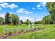 Expansive backyard featuring a white picket fence, arbor, landscape area with utility tower and shed under a partly cloudy sky at 5215 Limestone Ct, Indianapolis, IN 46237
