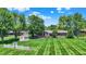 Large, manicured backyard with mature trees surrounding a single-story home with patio space at 5215 Limestone Ct, Indianapolis, IN 46237