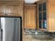 Close-up of wood kitchen cabinets, stainless steel fridge, and mosaic backsplash at 526 Emerson Rd, Carmel, IN 46032