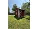 Red storage shed with white trim in a spacious, well-maintained backyard with lush green grass at 7607 Ardwell Ct, Indianapolis, IN 46237