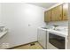 Functional laundry room with white washer and dryer units and oak cabinets above at 7741 Long Branch Dr, Indianapolis, IN 46259