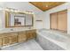 Bright main bathroom featuring double sink vanity, marble-surround tub and window at 7741 Long Branch Dr, Indianapolis, IN 46259