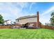 A charming backyard with a lush green lawn, a two-story house with a brick chimney, and a wooden fence at 8030 Parcrest Ct, Indianapolis, IN 46259