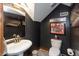 Stylish half bath with dark gray walls, decorative mirror and lighting, and neutral fixtures at 8140 Springwater W Dr, Indianapolis, IN 46256