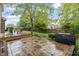 View of backyard showing wooden deck and stone patio with grill, surrounded by lush green lawn at 8663 N Commonview Dr, McCordsville, IN 46055