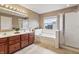 Bright bathroom featuring a double sink vanity, soaking tub, and glass shower door at 8663 N Commonview Dr, McCordsville, IN 46055