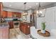 Well-lit kitchen boasts stainless appliances, wood cabinets, central island and a breakfast nook with a modern chandelier at 8663 N Commonview Dr, McCordsville, IN 46055