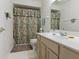 Well-lit bathroom with a single sink vanity, floral shower curtain, and tile flooring at 9175 Lakewind Dr, Indianapolis, IN 46256