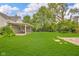 Beautiful backyard with well-maintained lawn, patio, and mature trees under a blue sky at 1141 N Shadeland Ave, Indianapolis, IN 46219