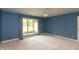 A spacious bedroom with blue walls, a large window, and neutral-toned carpeting at 1220 Pintail Ct, Columbus, IN 47201