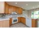 Functional kitchen featuring wood cabinets, tile floors, white appliances, and white countertops at 1220 Pintail Ct, Columbus, IN 47201