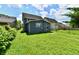 Wide-angle view of the backyard showing the green grass, a gray house with white-trimmed window, and wire fencing at 1346 W 27Th St, Indianapolis, IN 46208