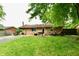 Brick home back exterior shows the yard with a small patio, grill and outdoor seating under a leafy tree at 1445 Biloxi Ln, Beech Grove, IN 46107