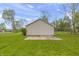 View of the backyard with a detached garage, a small patio area and lush green grass at 1535 Whalen Ave, Indianapolis, IN 46227