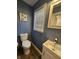 A well-lit bathroom showcasing a modern toilet, vanity with sink, and a framed mirror above the sink at 1628 Edgewood Dr, Anderson, IN 46011