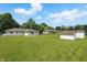 Large backyard with mature trees, lush green grass, and multiple storage sheds for outdoor equipment at 17 E Beechwood Ln, Indianapolis, IN 46227