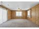 A living room with carpet, wood paneled walls, a ceiling fan, and windows at 17 E Beechwood Ln, Indianapolis, IN 46227