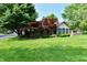 Landscaped yard and mature trees surround this charming single-story home with a brick chimney at 1783 Cloister Dr, Indianapolis, IN 46260