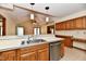 Open kitchen featuring wood cabinets, stainless steel appliances, and a breakfast bar under modern pendant lighting at 1783 Cloister Dr, Indianapolis, IN 46260