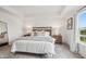 Bright main bedroom boasts tray ceilings, stylish decor, and a large window overlooking a well-maintained lawn at 19652 Shadow Trace Path, Westfield, IN 46074