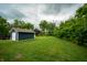 Wide backyard with a shed, mature trees, and well-maintained green lawn at 2159 W 58Th Nw St, Indianapolis, IN 46228
