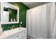 Green bathroom featuring a shower with shower curtain, sink with mirror and white cabinet at 3225 25Th St, Columbus, IN 47203