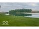Beautiful lake view with lush green grass and trees in the background on an overcast day at 3861 Indigo Blue Blvd, Whitestown, IN 46075