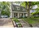 Inviting home with a covered front porch, surrounded by lush greenery and mature trees on a sunny day at 4619 N Park Ave, Indianapolis, IN 46205
