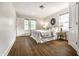 Bright main bedroom featuring hardwood floors, a cozy bed with white linens, and natural light from two windows at 4619 N Park Ave, Indianapolis, IN 46205