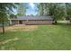 A large backyard with green grass surrounds a brick home with a patio and an area of landscaped shrubs at 4645 Quail Run Dr, New Palestine, IN 46163