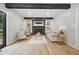 Cozy living room with black brick fireplace, wood beam, white shiplap ceiling and light wood floors at 4645 Quail Run Dr, New Palestine, IN 46163