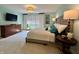 A well-lit bedroom featuring a tufted headboard, decorative chandelier, and a classic wooden dresser at 5491 Vin Rose Ln, Lawrence, IN 46226