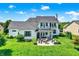 Aerial view of a manicured backyard with lush lawn, stone patio with firepit and covered living spaces at 6882 Bladstone Rd, Noblesville, IN 46062