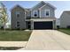 Charming two-story home featuring a gray brick and siding exterior, a black garage door, and a well-manicured lawn at 6883 Honeysuckle Way, Pendleton, IN 46064