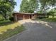 Charming brick home featuring a two-car garage and a long driveway lined with lush greenery and mature trees at 7088 Sandalwood Dr, Indianapolis, IN 46217