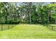 Lush backyard with a well-manicured lawn and mature trees, enclosed by a black metal fence, providing a serene outdoor space at 7154 Covington St, Lebanon, IN 46052