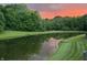 Scenic pond view reflecting a gorgeous sunset with trees surrounding the water's edge at 7212 Maple Bluff Pl, Indianapolis, IN 46236