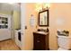 Charming bathroom with a wood vanity, decorative mirror, and adjacent laundry area at 7242 Highburry Dr, Indianapolis, IN 46256