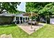 An inviting outdoor patio area with a dining table, umbrella, grill, and lovely green surroundings for entertaining at 7242 Highburry Dr, Indianapolis, IN 46256