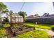 The backyard has a small greenhouse and raised garden beds surrounded by grass and a fence. There are other houses in the background at 743 Sanders St, Indianapolis, IN 46203