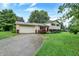 Well-kept two-story home with an attached garage and a long driveway, complemented by mature trees at 7504 Troon Ct, Indianapolis, IN 46237