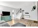 Open living room with wood-look floors, a modern TV console, and access to the staircase at 7504 Troon Ct, Indianapolis, IN 46237